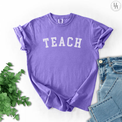 Violet t-shirt with 'TEACH' text on a white background