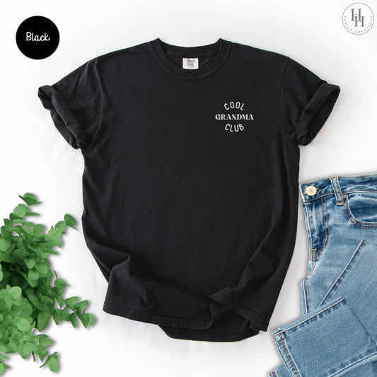 Black t-shirt with 'Cool Grandma Club' text on a white background with jeans and greenery.