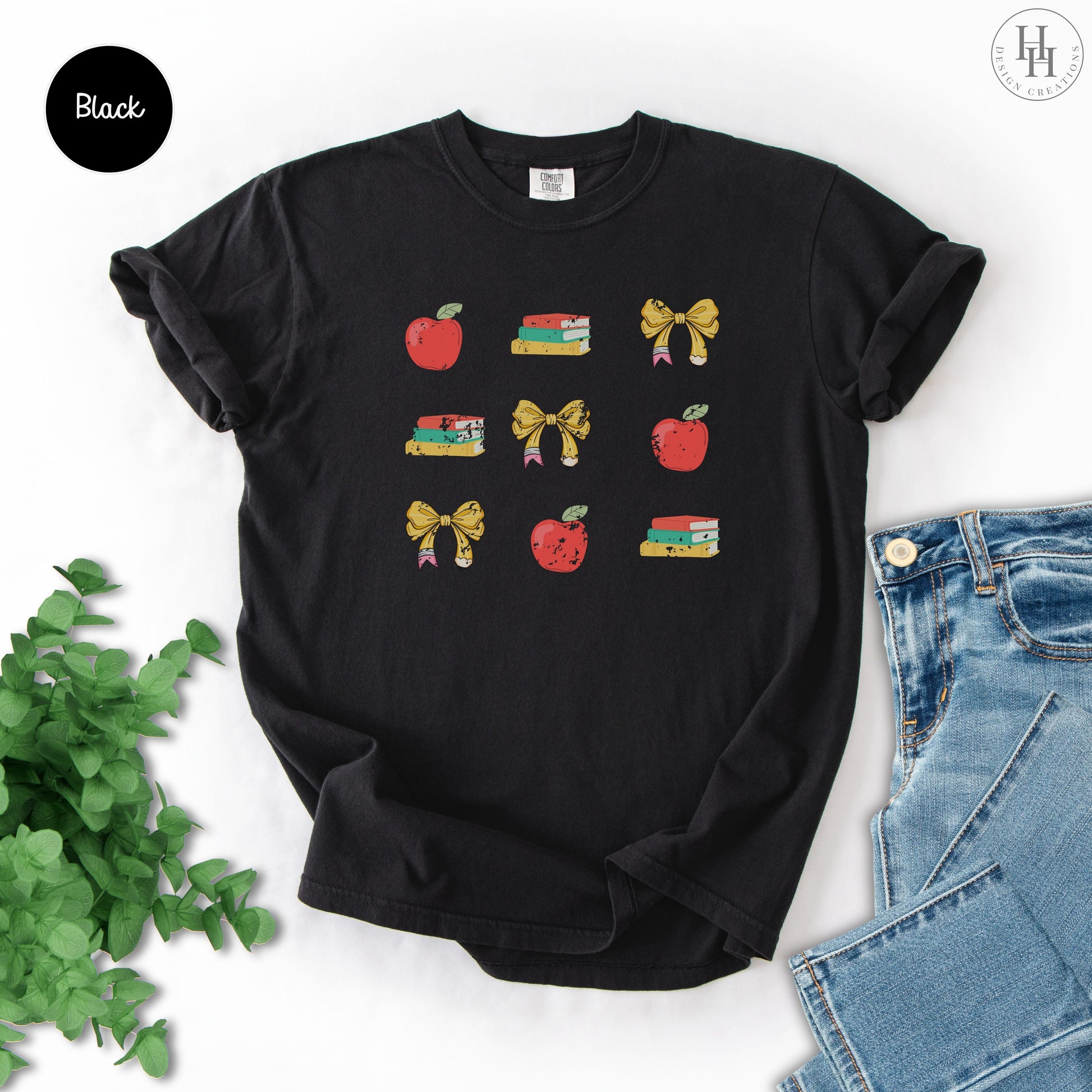 Black t-shirt with 'TEACHER' text on a white background with jeans and greenery.